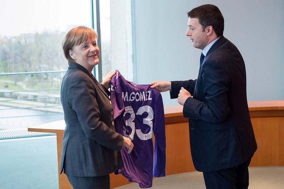 Missione compiuta: Matteo Renzi ha consegnato alla cancelliera Angela Merkel la maglia di Mario Gomez con dedica. 